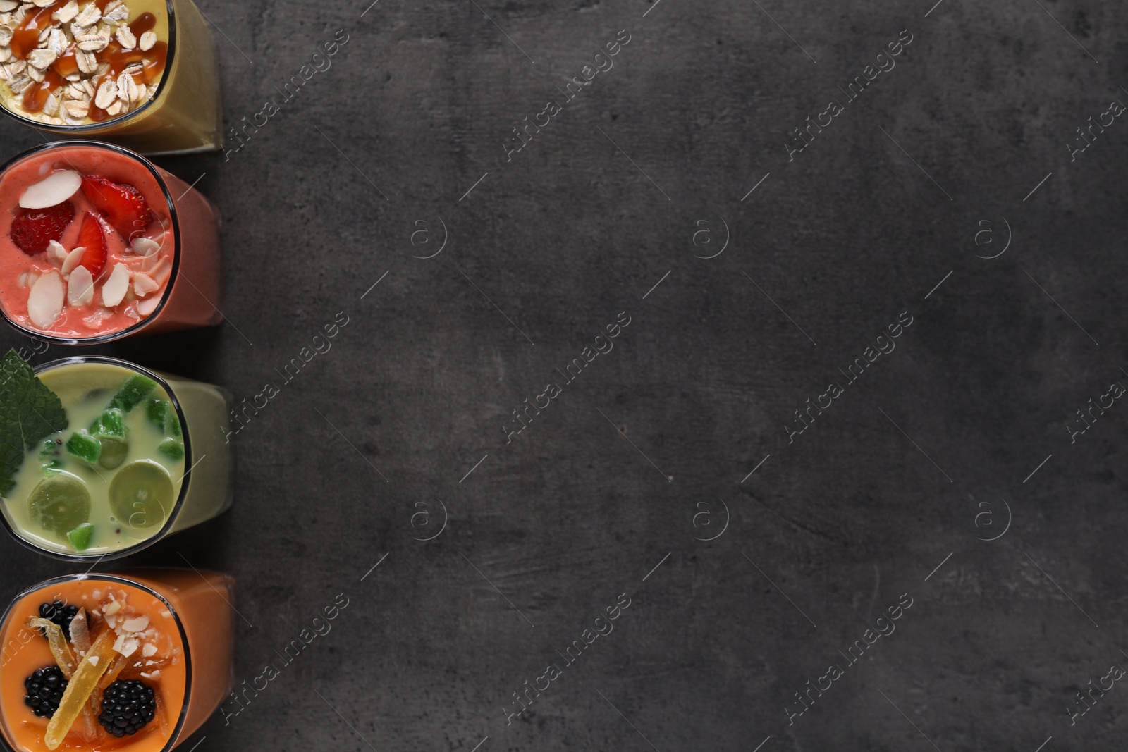 Photo of Many different delicious smoothies on grey table, flat lay. Space for text