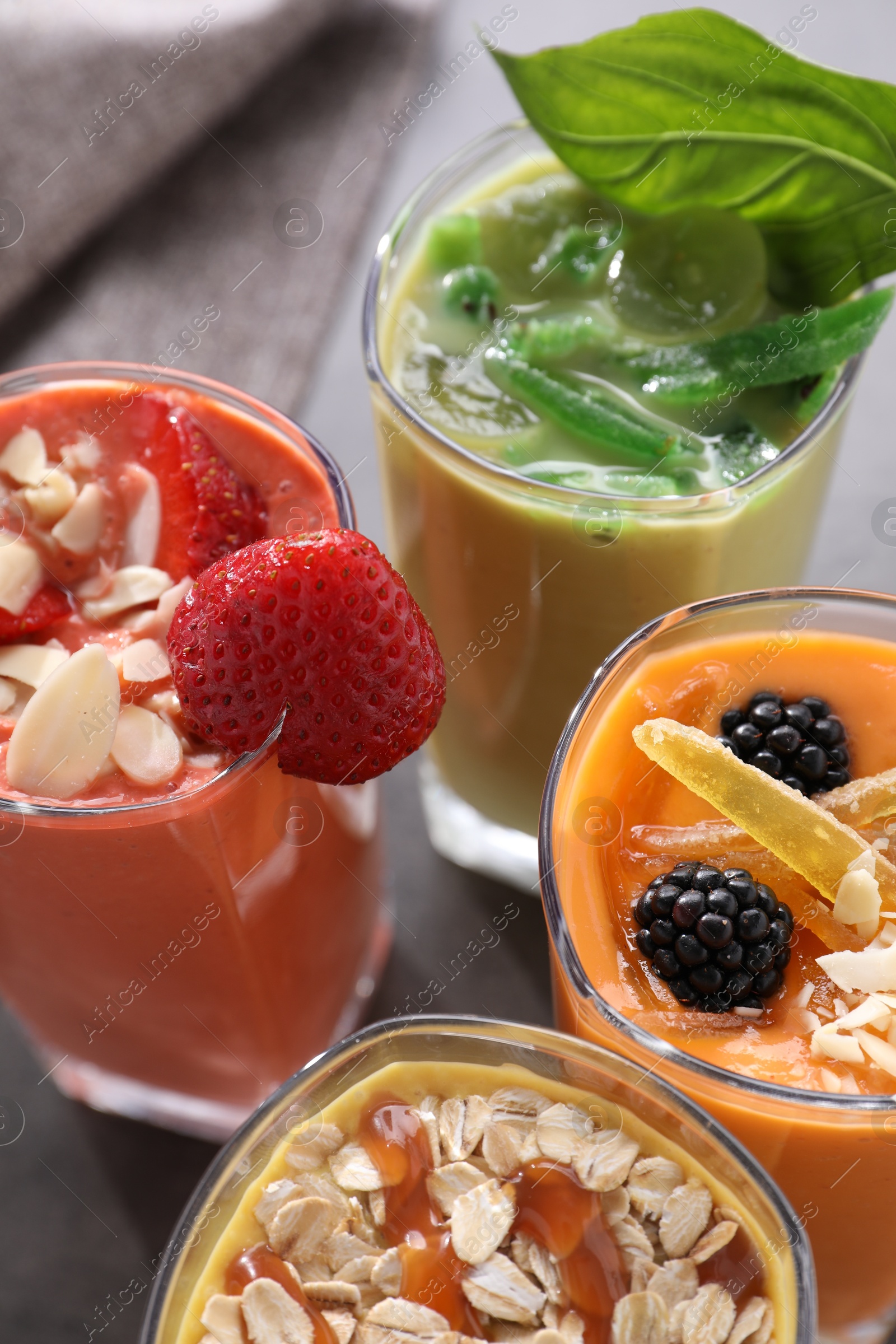 Photo of Many different delicious smoothies on grey table, closeup