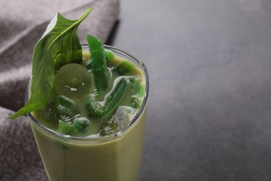 Photo of Glass of delicious smoothie with grape, candied kiwi and basil on grey table, closeup. Space for text