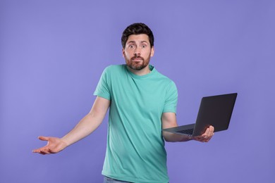 Photo of Confused man with laptop on purple background