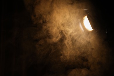 Photo of Professional spotlight and smoke in darkness. Space for text