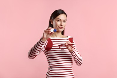 Photo of Woman choosing between glasses and contact lenses on pink background
