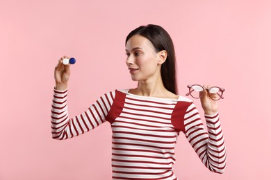 Photo of Woman choosing between glasses and contact lenses on pink background