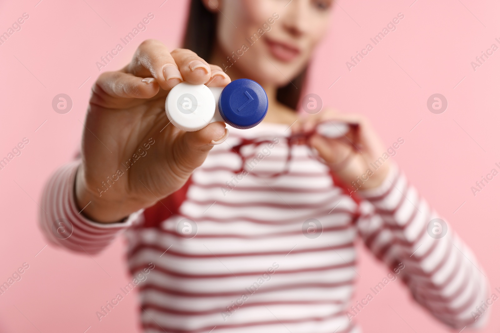Photo of Woman choosing between glasses and contact lenses on pink background, selective focus