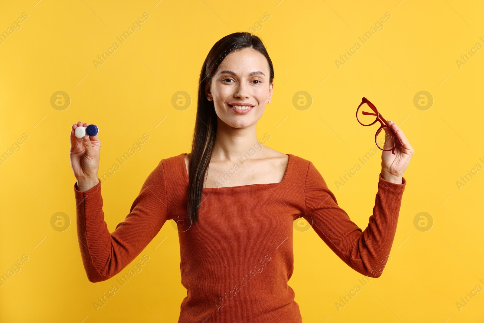 Photo of Woman choosing between glasses and contact lenses on orange background