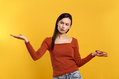 Photo of Woman choosing between glasses and contact lenses on orange background