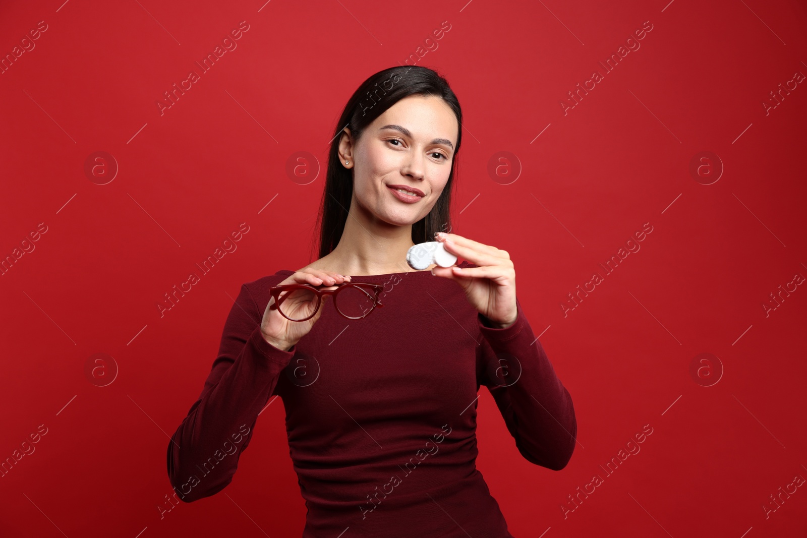 Photo of Woman choosing between glasses and contact lenses on red background