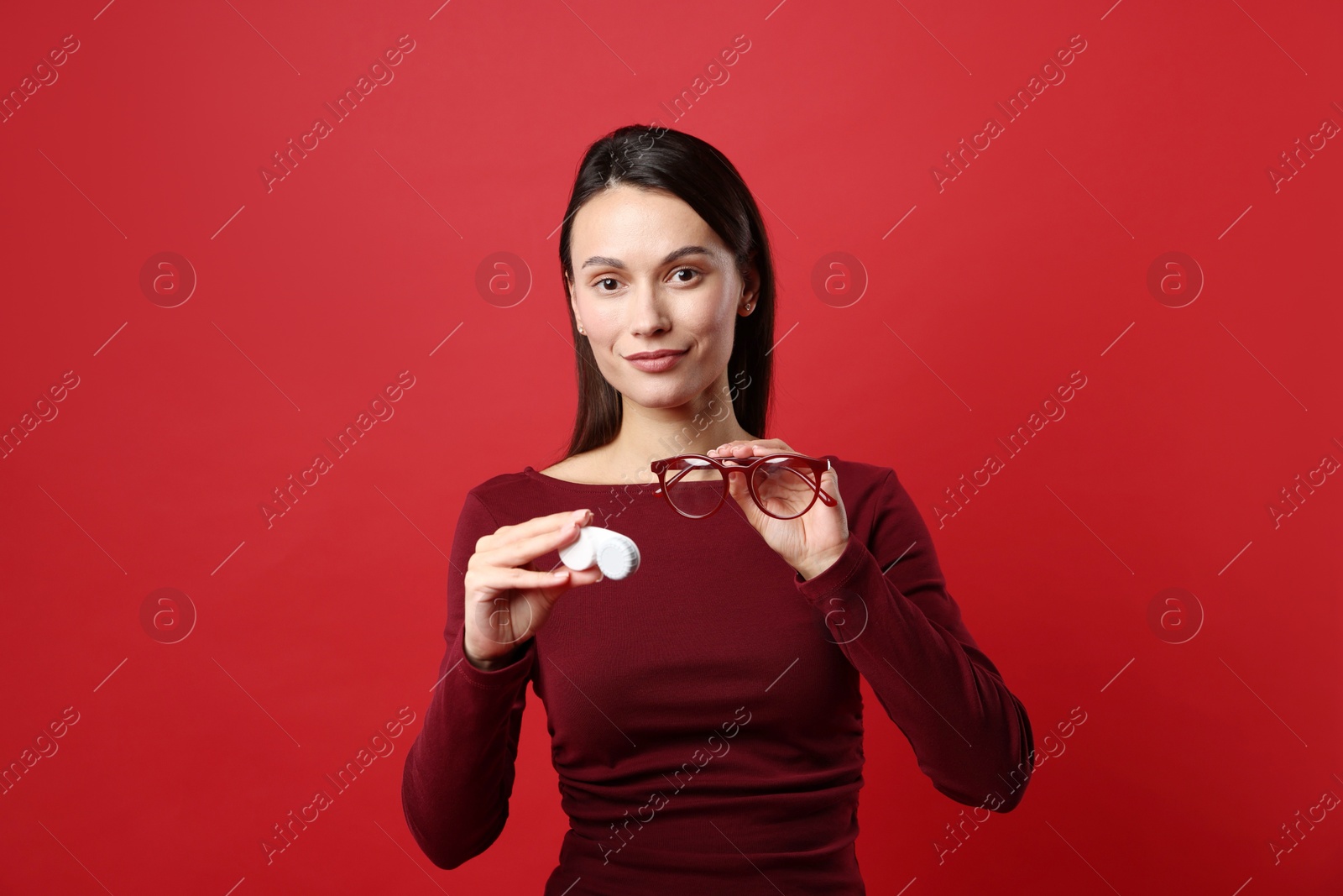 Photo of Woman choosing between glasses and contact lenses on red background