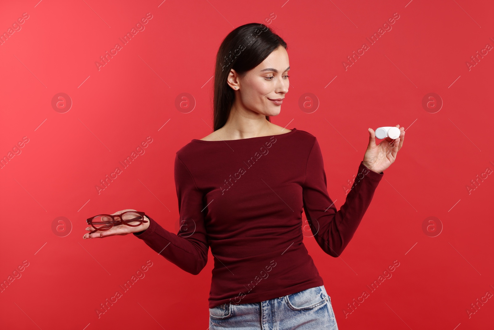 Photo of Woman choosing between glasses and contact lenses on red background