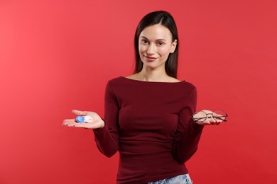 Photo of Woman choosing between glasses and contact lenses on red background