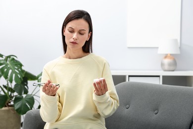 Photo of Woman choosing between glasses and contact lenses on sofa indoors, space for text