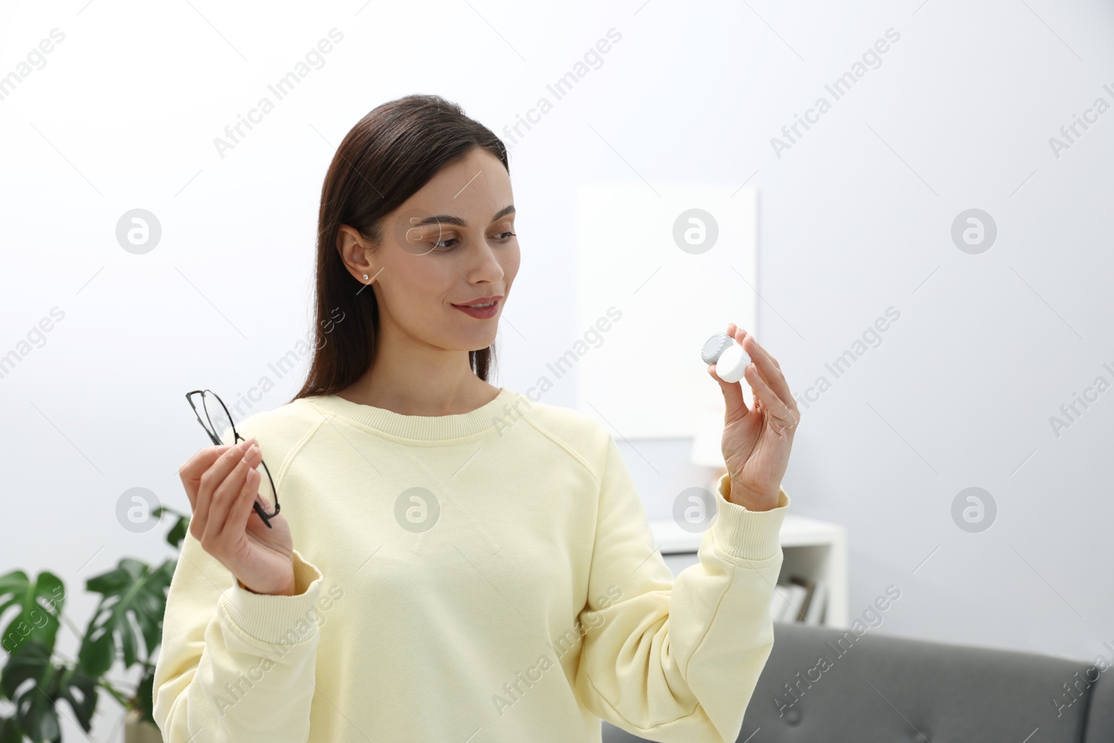 Photo of Woman choosing between glasses and contact lenses indoors
