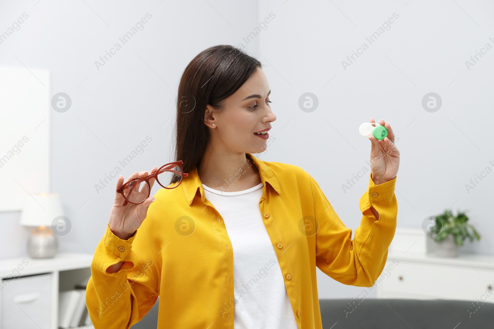 Photo of Woman choosing between glasses and contact lenses indoors