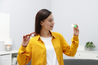 Photo of Woman choosing between glasses and contact lenses indoors