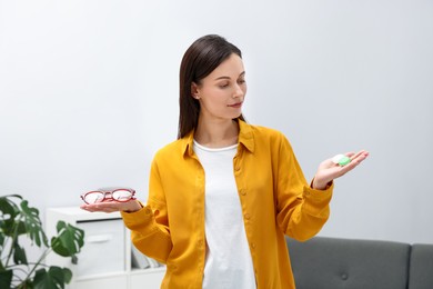 Photo of Woman choosing between glasses and contact lenses indoors
