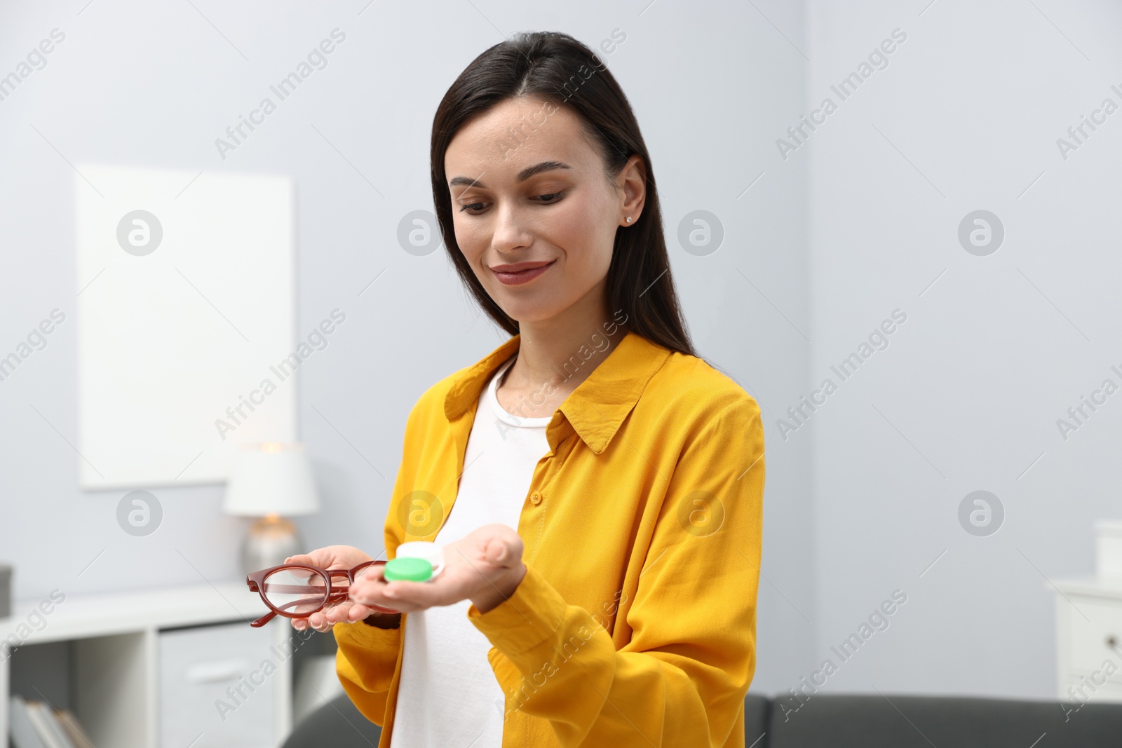 Photo of Woman choosing between glasses and contact lenses indoors