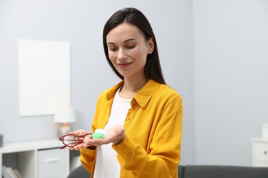 Photo of Woman choosing between glasses and contact lenses indoors