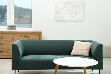 Photo of Comfortable sofa with pillow and side table indoors