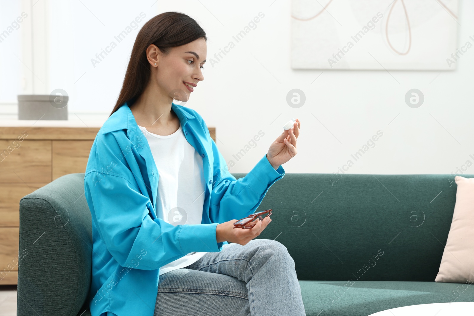 Photo of Woman choosing between glasses and contact lenses on sofa indoors, space for text