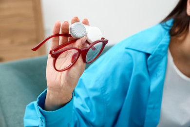Photo of Woman choosing between glasses and contact lenses indoors, closeup