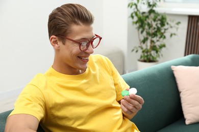 Photo of Man in glasses with contact lenses on sofa indoors