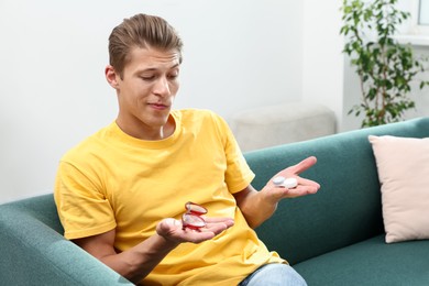 Photo of Man choosing between glasses and contact lenses on sofa indoors