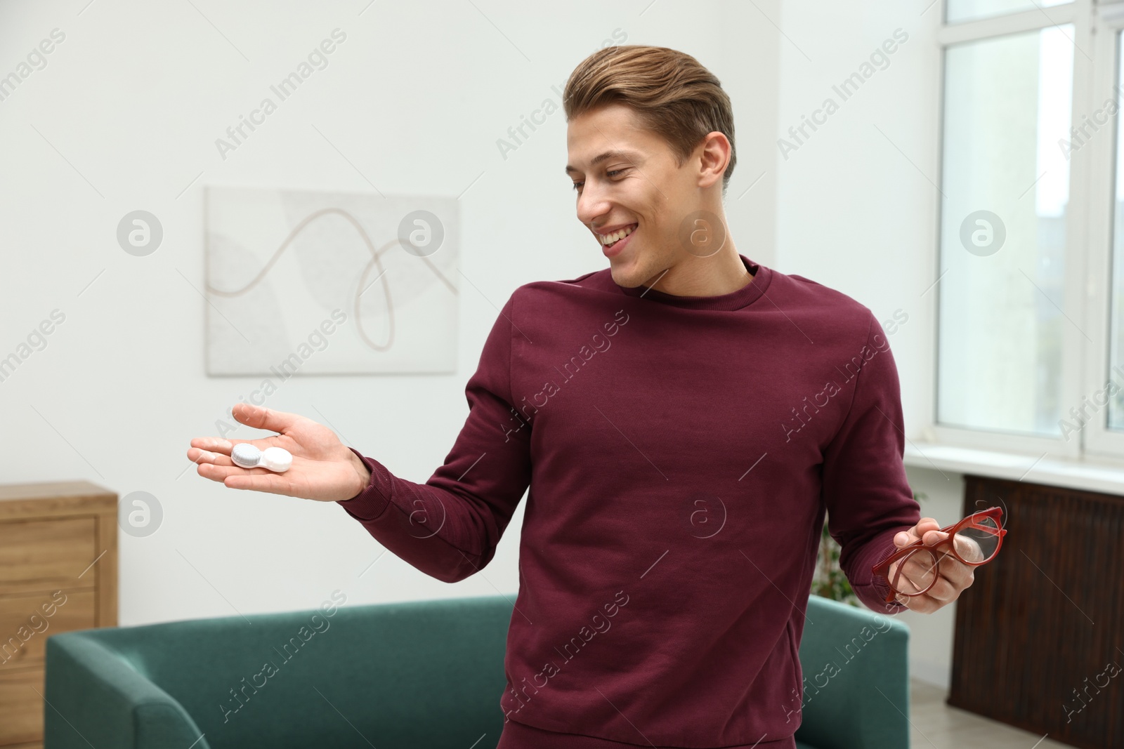 Photo of Man choosing between glasses and contact lenses indoors