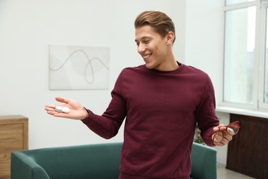 Photo of Man choosing between glasses and contact lenses indoors