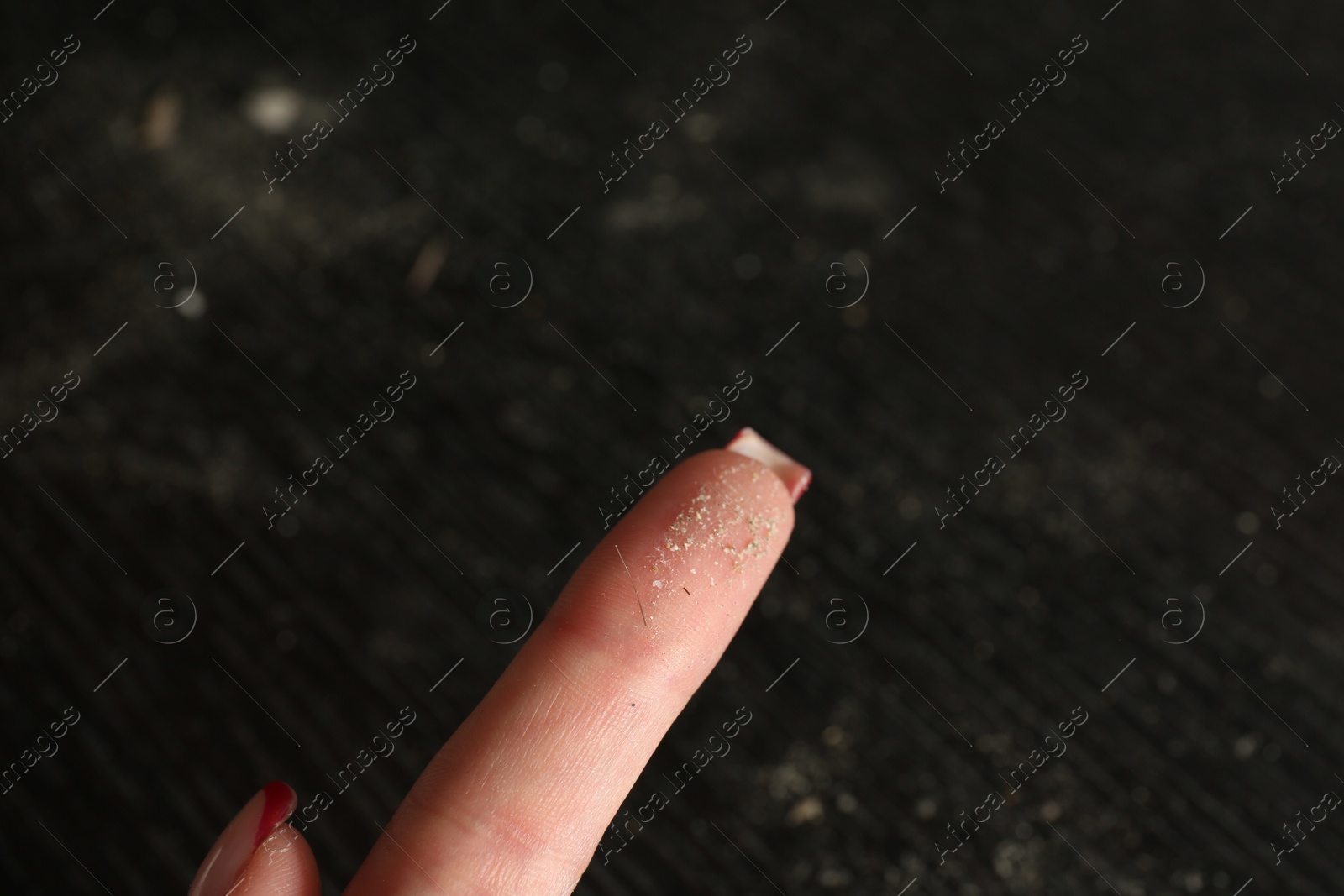 Photo of Woman swiping dust from black wooden table, closeup