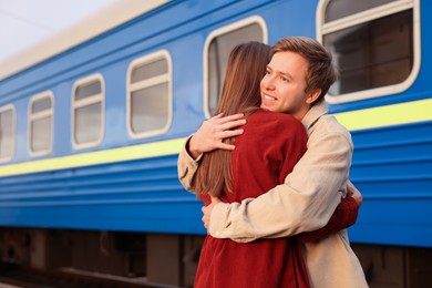 Photo of Goodbye. Lovely couple hugging on platform of railway station, space for text