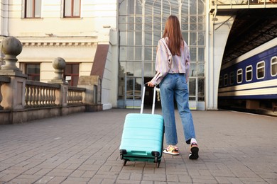 Photo of Goodbye. Woman with luggage on platform of railway station, back view. Space for text