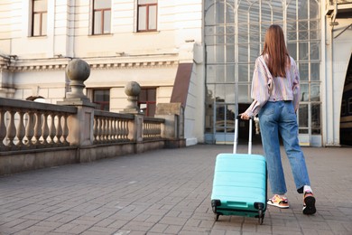 Photo of Goodbye. Woman with luggage on platform of railway station, back view. Space for text