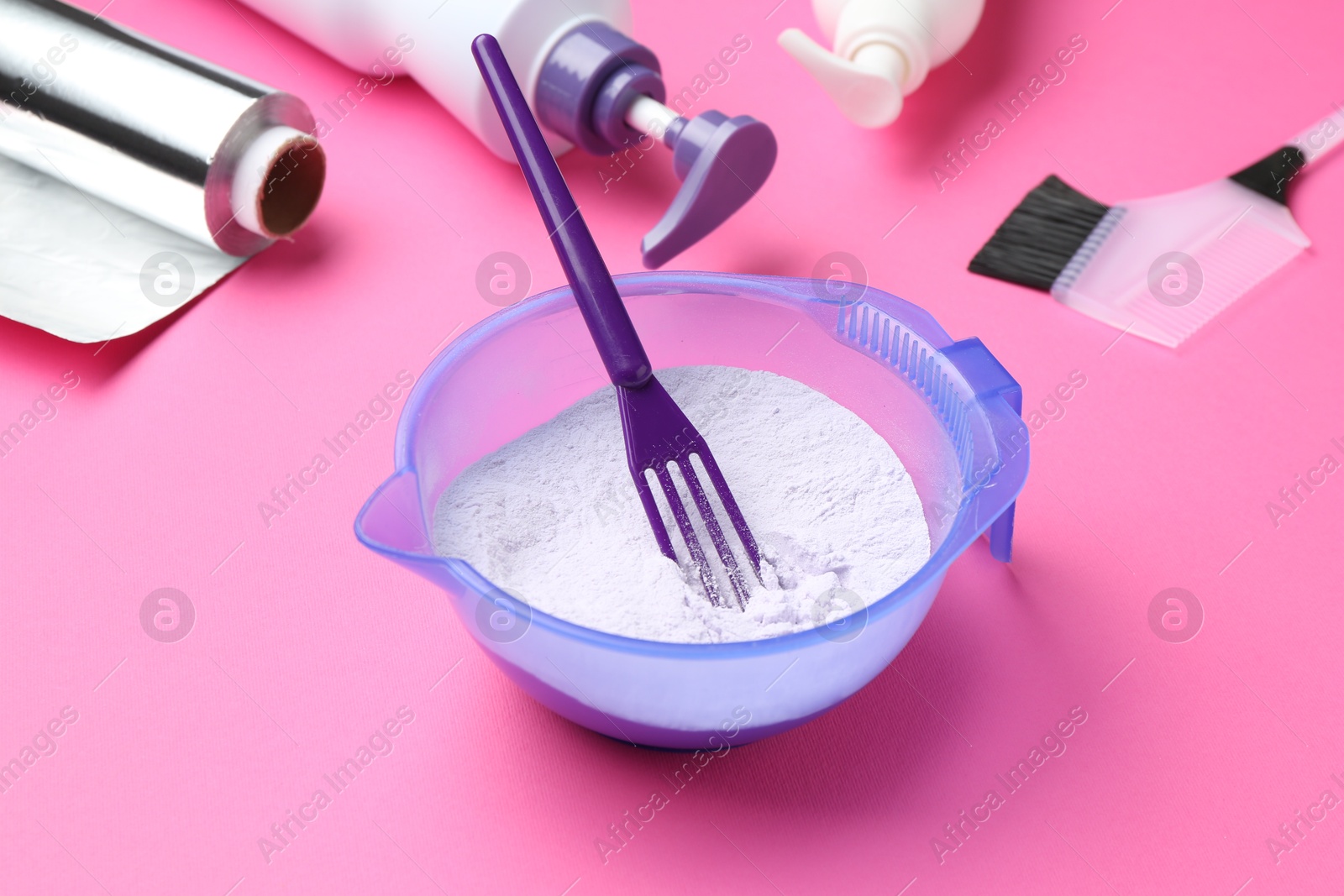 Photo of Care cosmetic product for blonde hair in bowl and hairdresser's tools on pink background, closeup