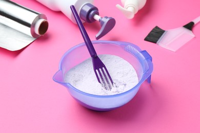 Photo of Care cosmetic product for blonde hair in bowl and hairdresser's tools on pink background, closeup