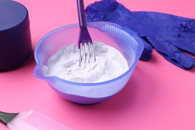Photo of Care cosmetic product for blonde hair in bowl and hairdresser's tools on pink background, closeup