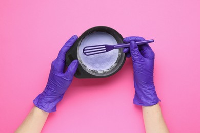 Photo of Woman making hair care product for blonde hair on pink background, top view