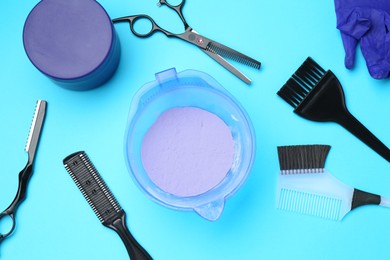 Photo of Care cosmetic product for blonde hair in bowl and hairdresser's tools on light blue background, flat lay