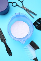 Photo of Care cosmetic product for blonde hair in bowl and hairdresser's tools on light blue background, flat lay