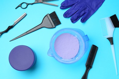 Photo of Care cosmetic product for blonde hair in bowl and hairdresser's tools on light blue background, flat lay