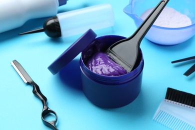 Photo of Care cosmetic product for blonde hair in jar and hairdresser's tools on light blue background, closeup