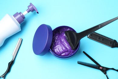 Photo of Care cosmetic product for blonde hair in jar and hairdresser's tools on light blue background, flat lay