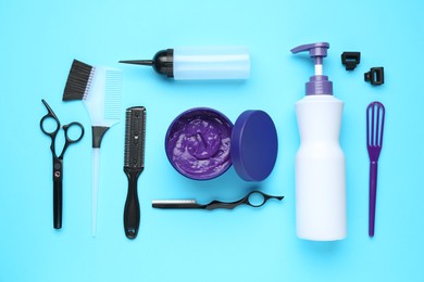 Photo of Care cosmetic product for blonde hair in jar and hairdresser's tools on light blue background, flat lay