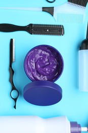 Photo of Care cosmetic product for blonde hair in jar and hairdresser's tools on light blue background, flat lay