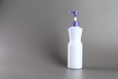Photo of Hair care product for blonde hair in bottle on grey background, space for text