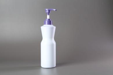 Photo of Hair care product for blonde hair in bottle on grey background, space for text