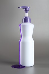Photo of Hair care product for blonde hair in bottle on grey background