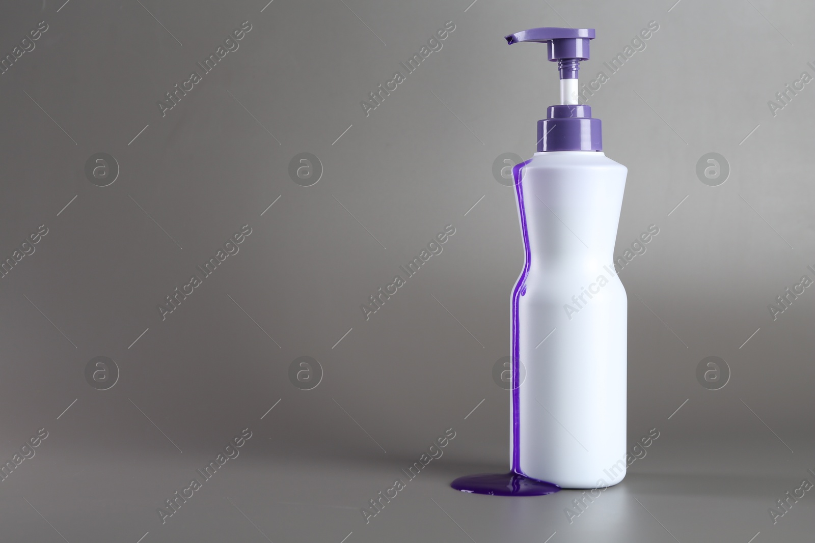 Photo of Hair care product for blonde hair in bottle on grey background, space for text