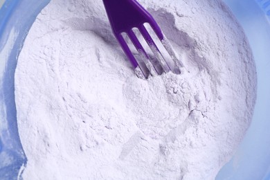 Photo of Hair care product for blonde hair and spatula in bowl, top view