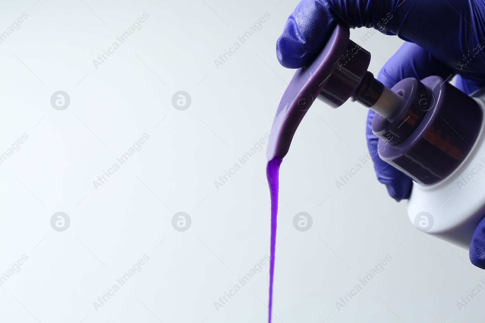 Photo of Woman pouring hair care product for blonde hair from bottle on white background, closeup. Space for text