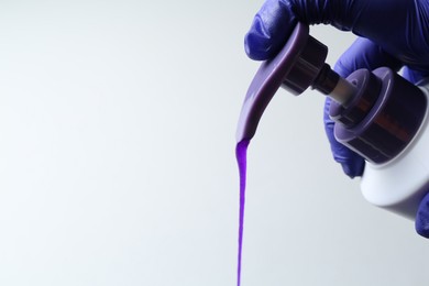 Photo of Woman pouring hair care product for blonde hair from bottle on white background, closeup. Space for text